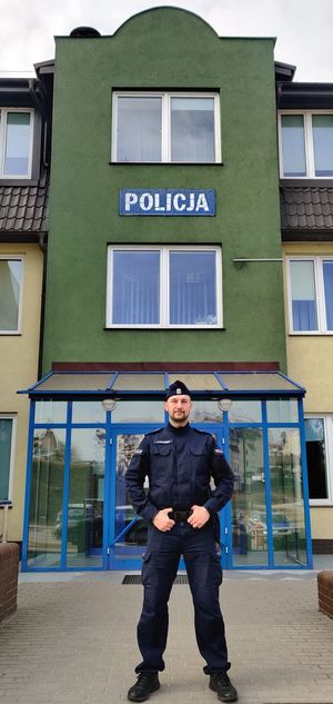 policjant stoi przed budynkiem jednostki Policji