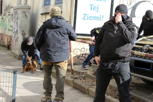 policjanci podczas akcji zatrzymania mężczyzny, jeden z nich trzyma psa