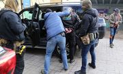 policjanci z zatrzymanym mężczyzną w kajdankach opartym o auto