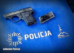 Zabytkowy pistolet na niebieskiej torbie z napisem Policja