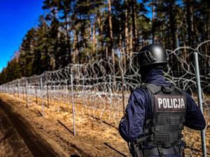 policjant stoi przy płocie granicznym