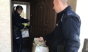 policjant i policjantka z darami wchodzą do mieszkania