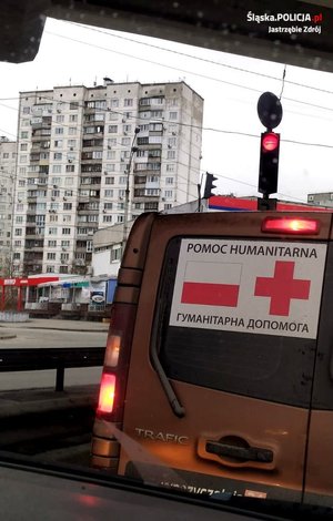 Zdjęcie przedstawiające samochód przewożący dary oraz miasto Kijów