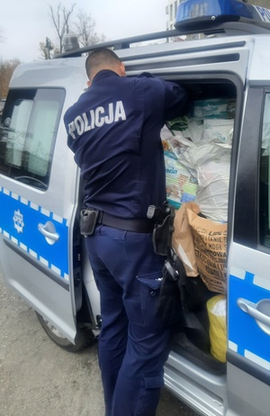 policjanci noszą paczki z darami dla uchodźców