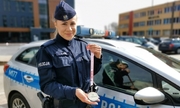umundurowana policjantka stoi przy radiowozie, w ręku trzyma medal za udział w mistrzostwach Polski kickboxingu
