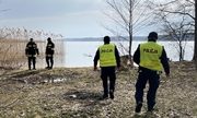 policjanci wspólnie ze strażakami szukają zaginionej na terenie leśnym, przy brzegu zbiornika wodnego