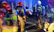 &quot;Na zdjęciu widoczni strażacy przez zadymionym budynkiem mieszkalnym, w którym wybuchł pożar