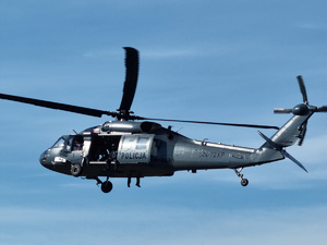 Policyjny Black Hawk podczas lotu na tle niebieskiego nieba.