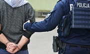 policjanci trzymają zatrzymanego mężczyznę w kajdankach