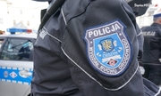 widoczna naszywka z napisem policja Cieszyn Wydział Ruchu Drogowego na mundurze policjanta stojącego przy radiowozie