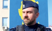 sierż. szt. Andrzej Dmytrenko na tle niebieskiego muralu z żółtym napisem Chwała Ukrainie