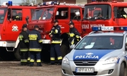 strażacy przy wozach strażackich i  radiowóz policyjny