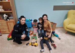 Policjanta kuca przy dzieciach z ich matką w niebieskim pokoju