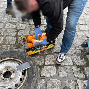 policjant wyciąga worek z marihuana ze skrzynki z pomarańczami