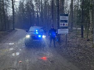policjant stoi przy samochodzie terenowym na drodze w lesie