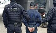 umundurowani policjanci, którzy maj napis: wydział kryminalny na plecach, prowadzą zatrzymanego mężczyznę