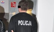 Zatrzymany oszust w czarnej bluzie z napisem: Policja prowadzony przez policjanta