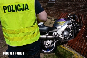 Policjant przy motocyklu który uderzył w ogrodzenie