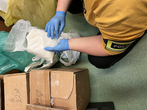 policjant trzyma woreczek foliowy z narkotykami