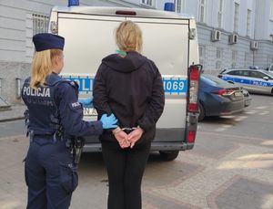 umundurowana policjantka prowadzi zatrzymaną kobietę