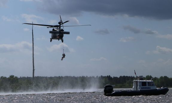 Black Hawk wraz z opuszczanym na linach ratownikiem oraz łódź policyjna na wodach Zalewu Zegrzyńskiego