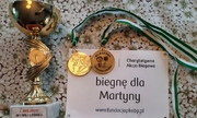 Puchar, dwa medale i kartka z napisem Biegnę dla Martynki