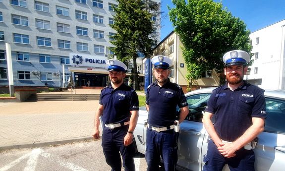 Trzej umundurowani policjanci stojący obok siebie na tle budynku Komendy Miejskiej Policji w Białymstoku