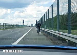 Rowerzysta jadący pasem awaryjnym po drodze ekspresowej