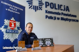 umundurowany policjant z nagrodami za wyniki sportowe siedzi za biurkiem