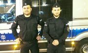 dwaj policjanci stojący obok radiowozu