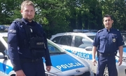 dwaj policjanci stoją przy radiowozie