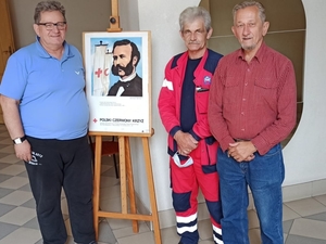 trzej mężczyźni stoją przy sztaludze z plakatem