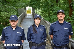 dwaj policjanci i policjantka stoją przed zamkniętym mostem