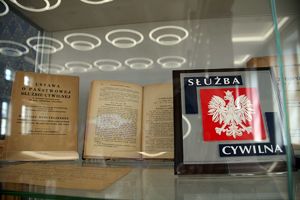 dwie książki w szklanej gablocie, jedna zatytułowana: Ustawa o Państwowej Służbie Cywilnej, obok  w ramce obrazek: orzeł w koronie i napis: Służba Cywilna