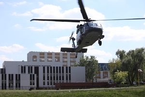 Black Hawk podczas startu, w tle budynki kompleksu szpitalnego oraz urządzenie wskazujące siłę wiatru.