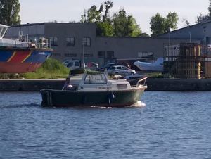 łódź policyjna na zbiorniku wodnym, w tle budynki na brzegu