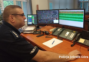 policjant dyżurny siedzi przed komputerem na stanowisku służby