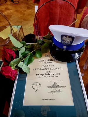 Certyfikat, czapka policyjna oraz kwiaty