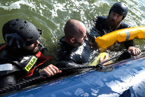 Policyjni ratownicy przy burcie pontonowej łodzi z uratowanym mężczyzną.