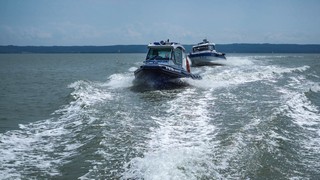 Dwie policyjne łodzie patrolujące płynna po spokojnym morzu.