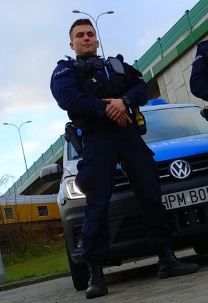policjant stoi przed radiowozem