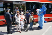 Na zdjęciu widać seniorów wychodzących z tramwaju. Wita ich policjantka i strażak oraz maskotka śląskiej Policji - pies Sznupek