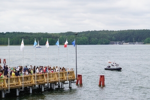 łódź policyjna na jeziorze, po prawej stronie widzowie stoją na pomoście