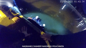 zdjęcie z kamery nasobnej policjanta, widok na kanał portowy, w wodzie znajduje się policjant z kołem ratunkowym i zaginiony mężczyzna