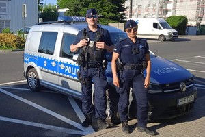 policjantka i policjant stoją przy radiowozie