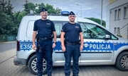 dwóch policjantów w mundurze stoi przy radiowozie