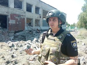 ukraiński policjant przed zbombardowanym budynkiem