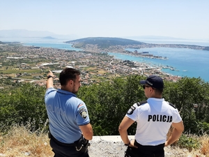 Zdjęcie dwóch umundurowanych policjantów polskiego i chorwackiego na tle widoku na zatokę morską