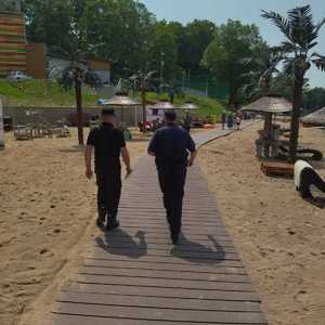 Policjant i strażak idą wzdłuż plaży.