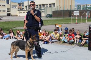 Policjant i pies służbowy wokół nich siedzą dzieci.